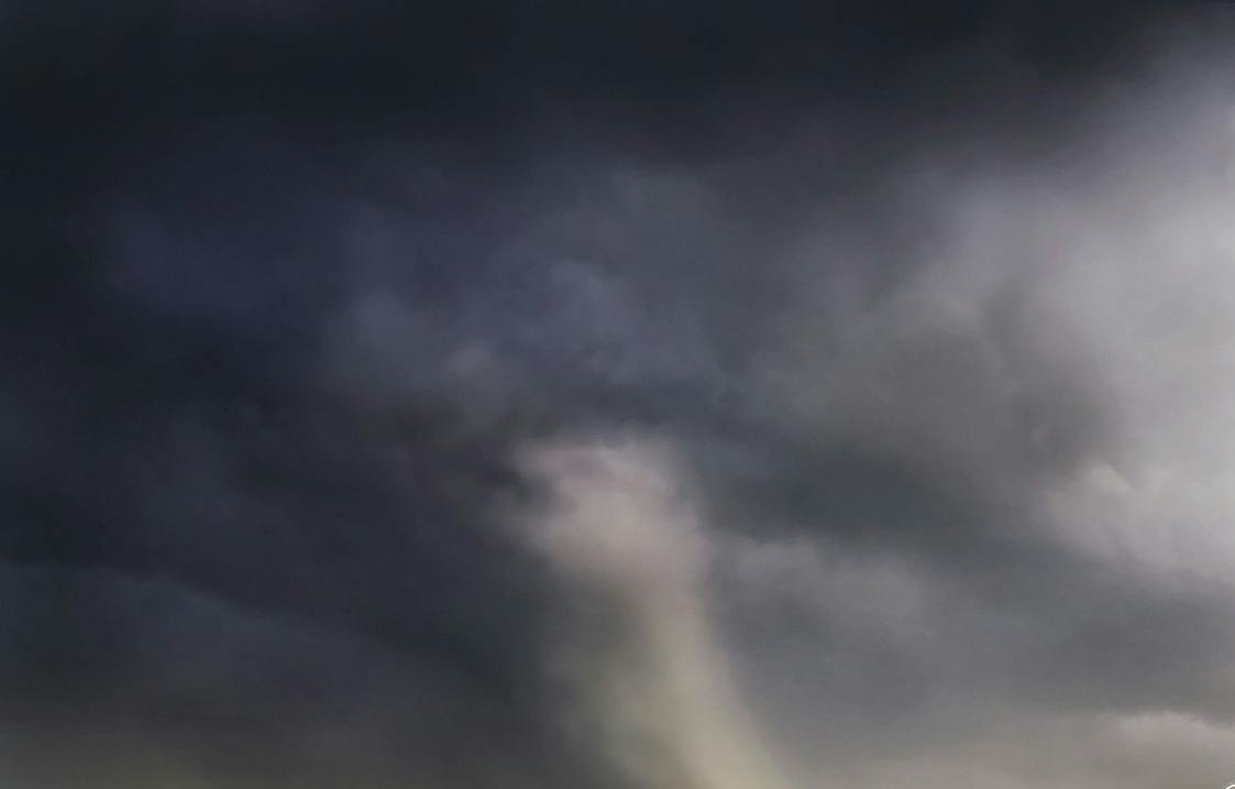 A powerful tornado and vibrant lightning striking over a rural countryside landscape.